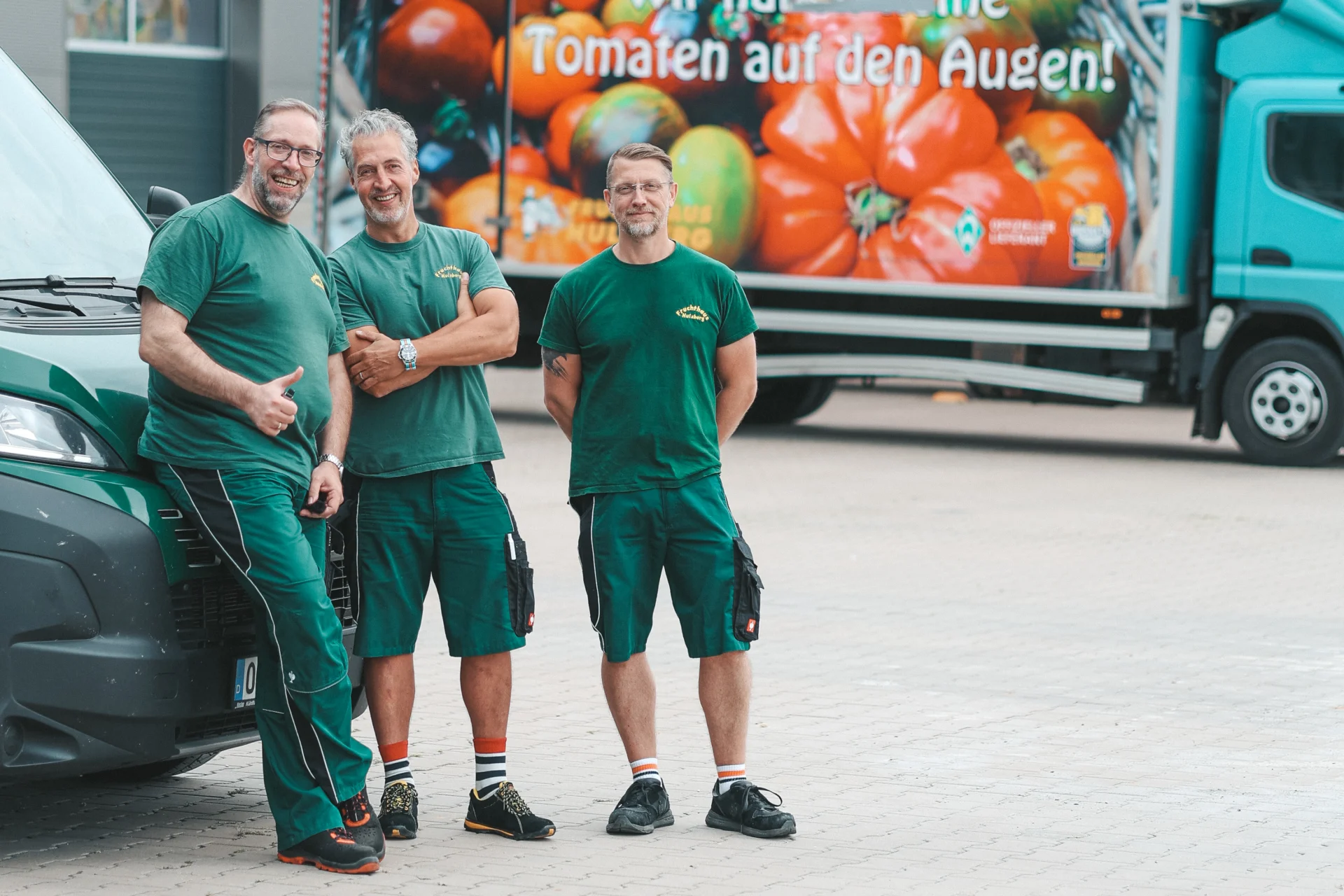 Mitarbeiter des Fruchthauses vor einem gebrandeten Lieferfahrzeug